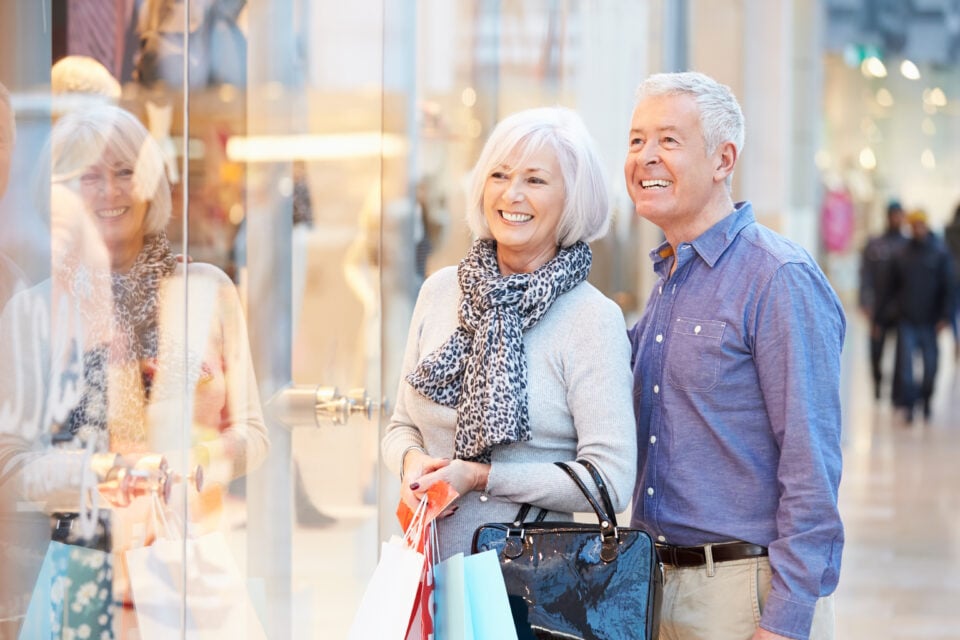 Happy Senior Couple Carrying Bags In Shopping Mall