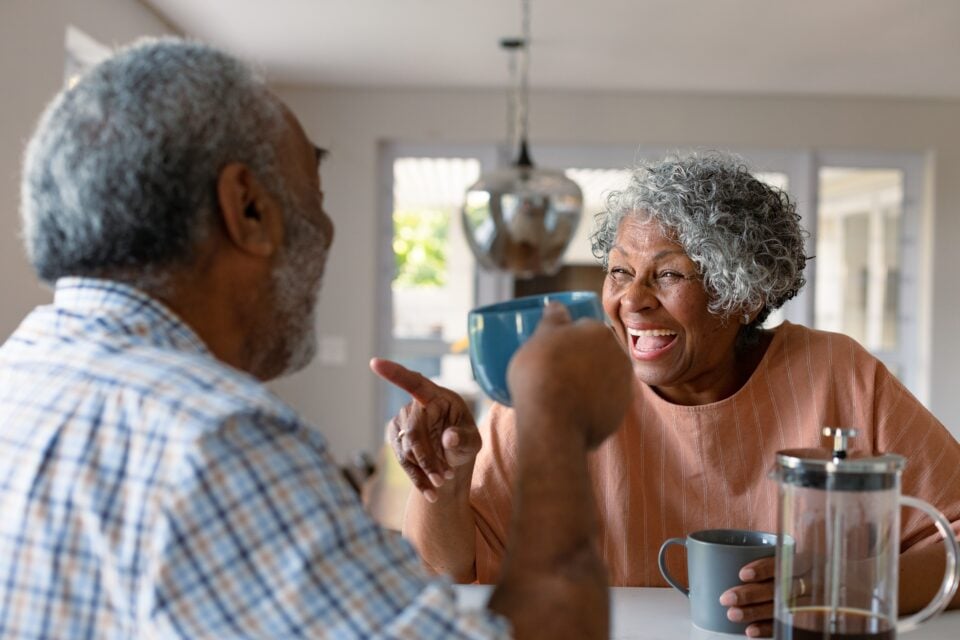 Happy,Senior,Couple,Sitting,In,Kitchen,With,Coffee